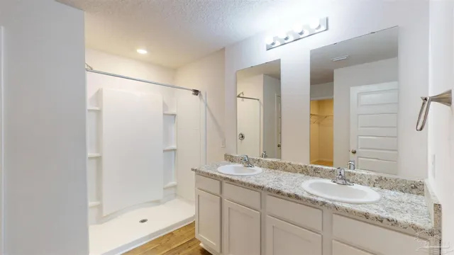 a bathroom with a granite countertop sink mirror and shower