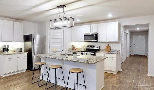 a kitchen with kitchen island granite countertop stainless steel appliances cabinets a sink and a island