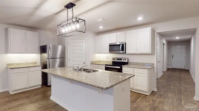 a kitchen with kitchen island granite countertop stainless steel appliances cabinets a sink and a counter top space