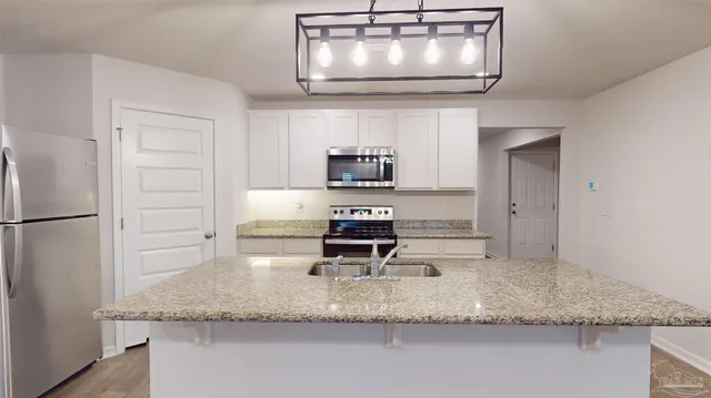 a kitchen with granite countertop a stove a microwave and refrigerator