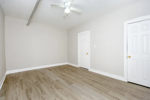 an empty room with wooden floor and fan