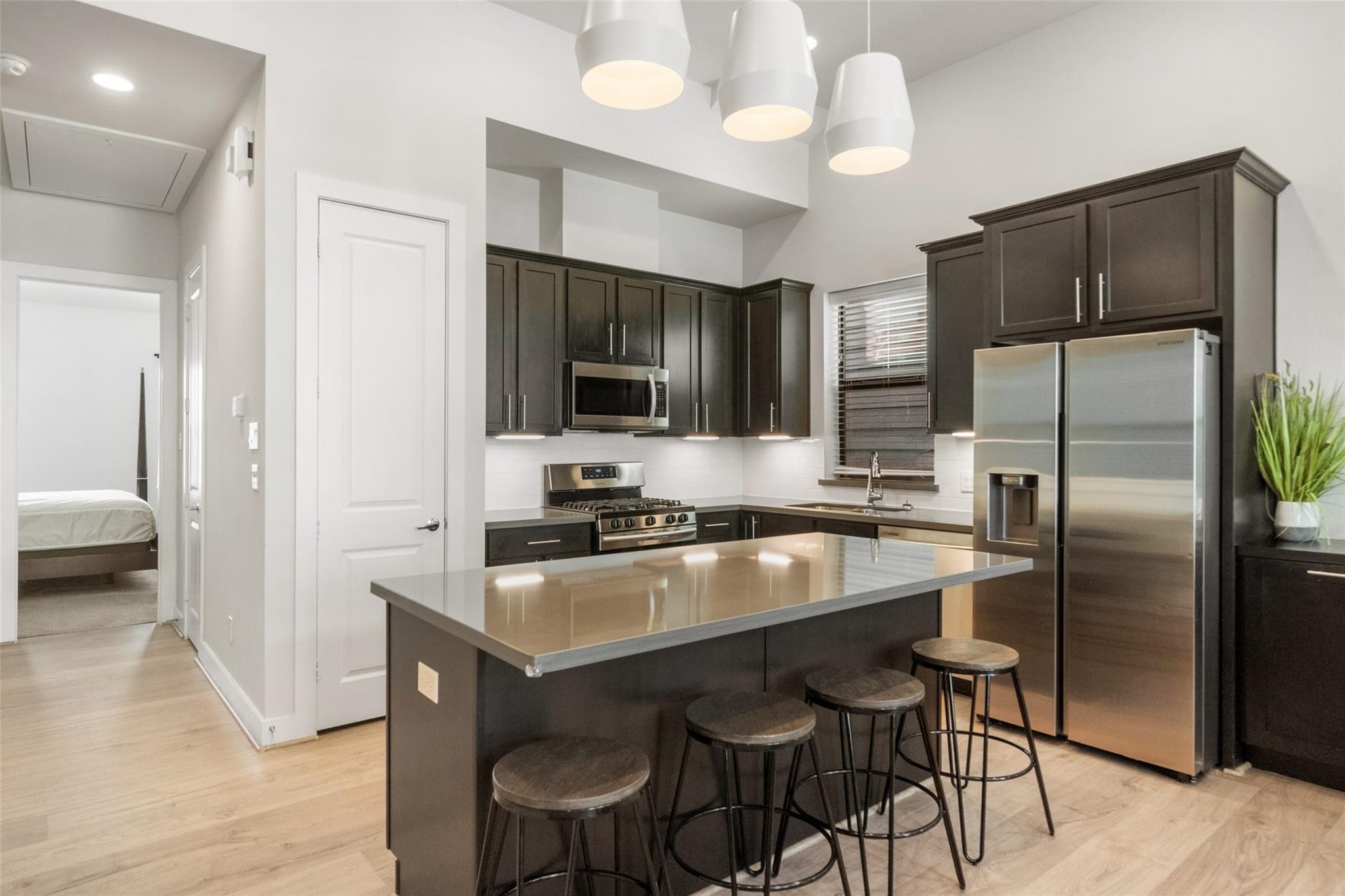 2616 Riverside Drive, Unit M Houston, TX 77004 - Photo 15 of 28 a kitchen with stainless steel appliances a refrigerator a stove a sink a dining table and chairs with wooden floor