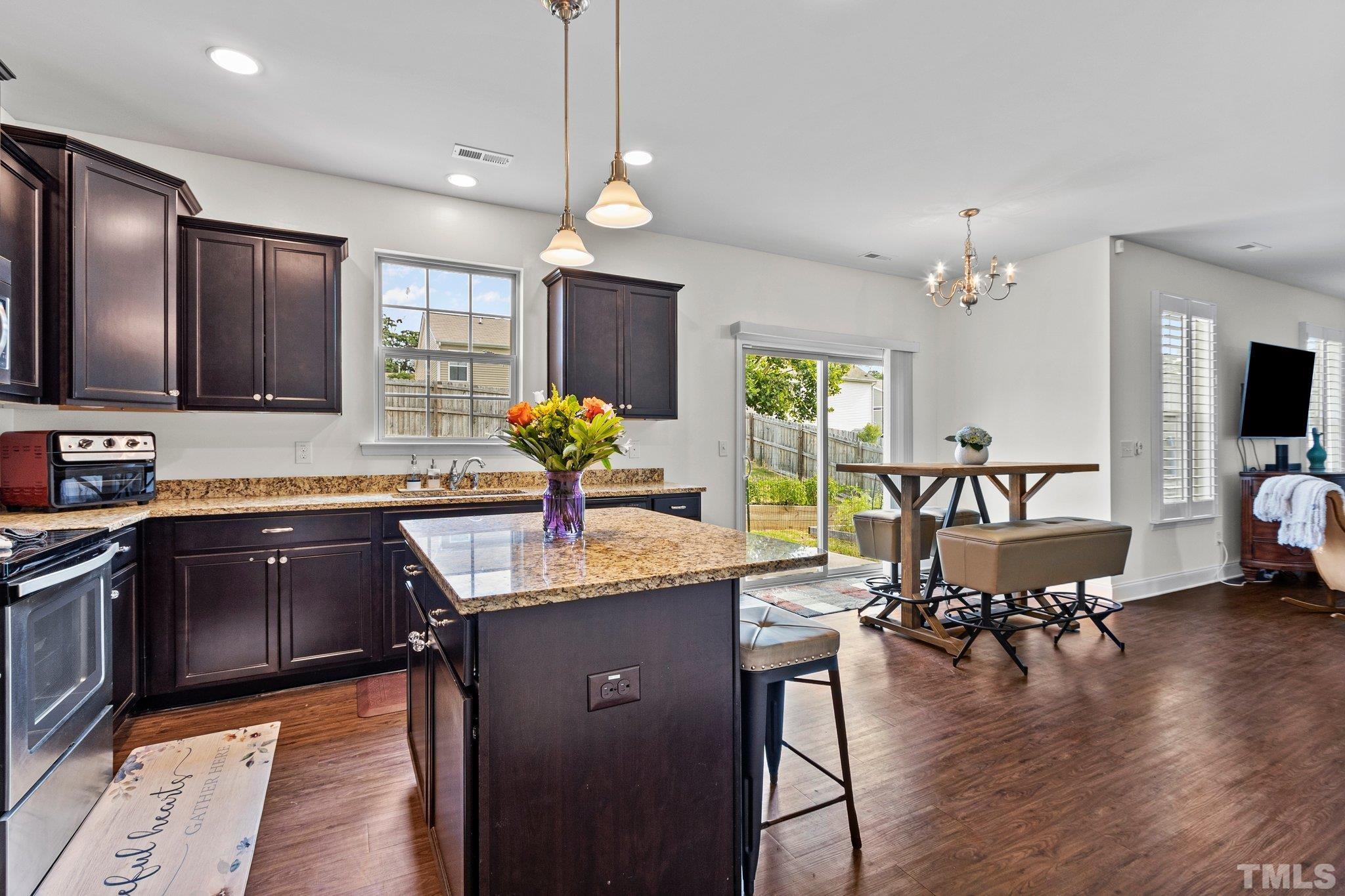 3229 Revelation Street Raleigh, NC 27610 - Photo 22 of 45 a kitchen with granite countertop a stove a sink a dining table and chairs