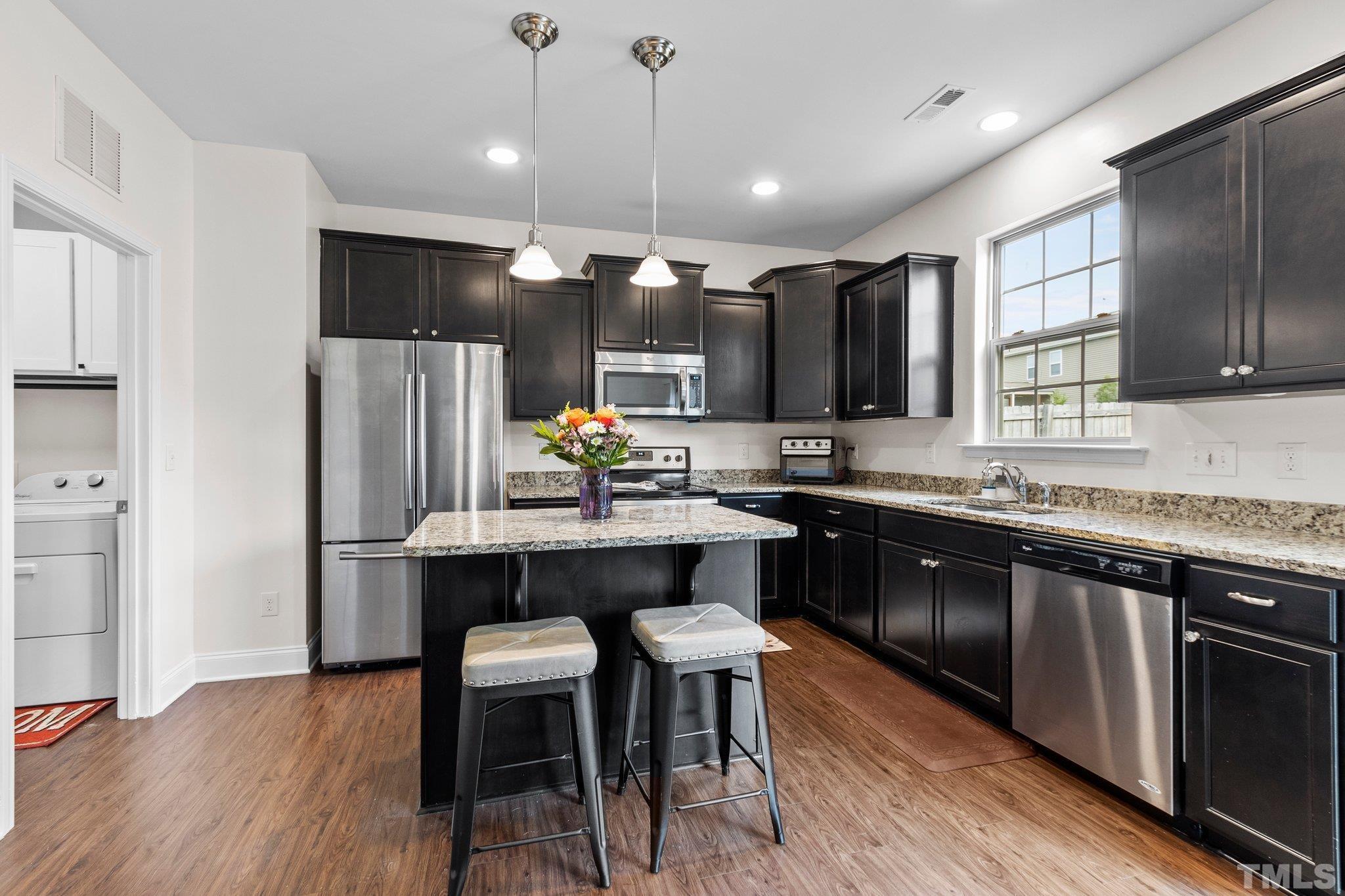 3229 Revelation Street Raleigh, NC 27610 - Photo 24 of 45 a kitchen with stainless steel appliances a dining table chairs refrigerator and microwave