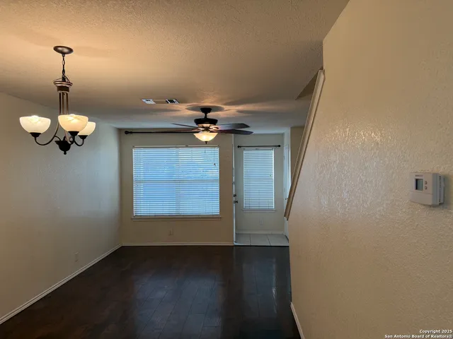 a view of a room with a chandelier fan and wooden floor