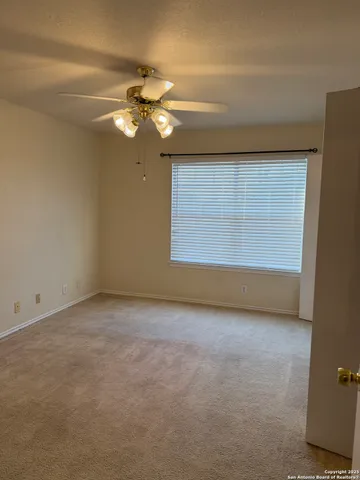 an empty room with a chandelier fan and windows