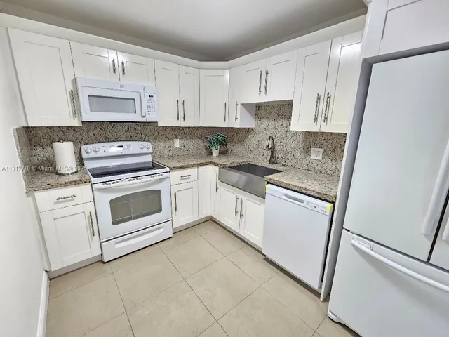 a white kitchen with granite countertop white stainless steel appliances
