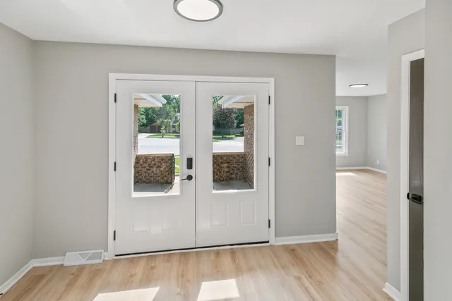 an empty room with wooden floor and windows