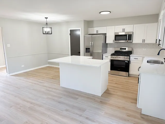 a kitchen with granite countertop a stove top oven and refrigerator