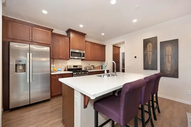 a kitchen with stainless steel appliances granite countertop a refrigerator a stove a sink a dining table and chairs