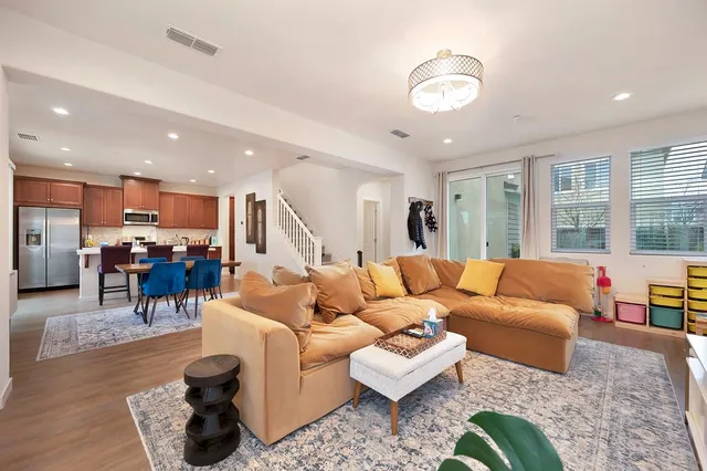 a living room with furniture kitchen view and a large window