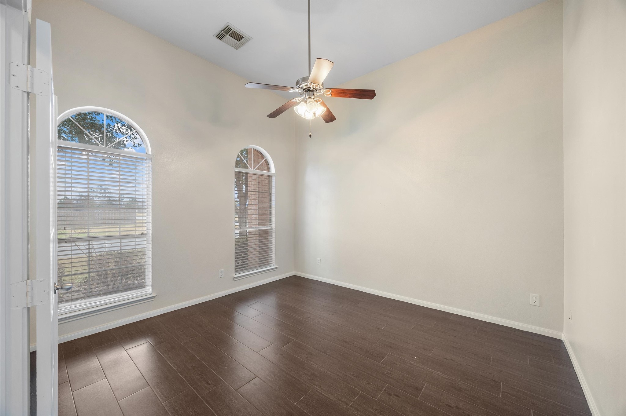 24538 Fort Settlement Drive Spring, TX 77373 - Photo 13 of 29 This room features high ceilings and dark wood flooring, with two large arched windows that let in ample natural light. A ceiling fan is centrally located for comfort.