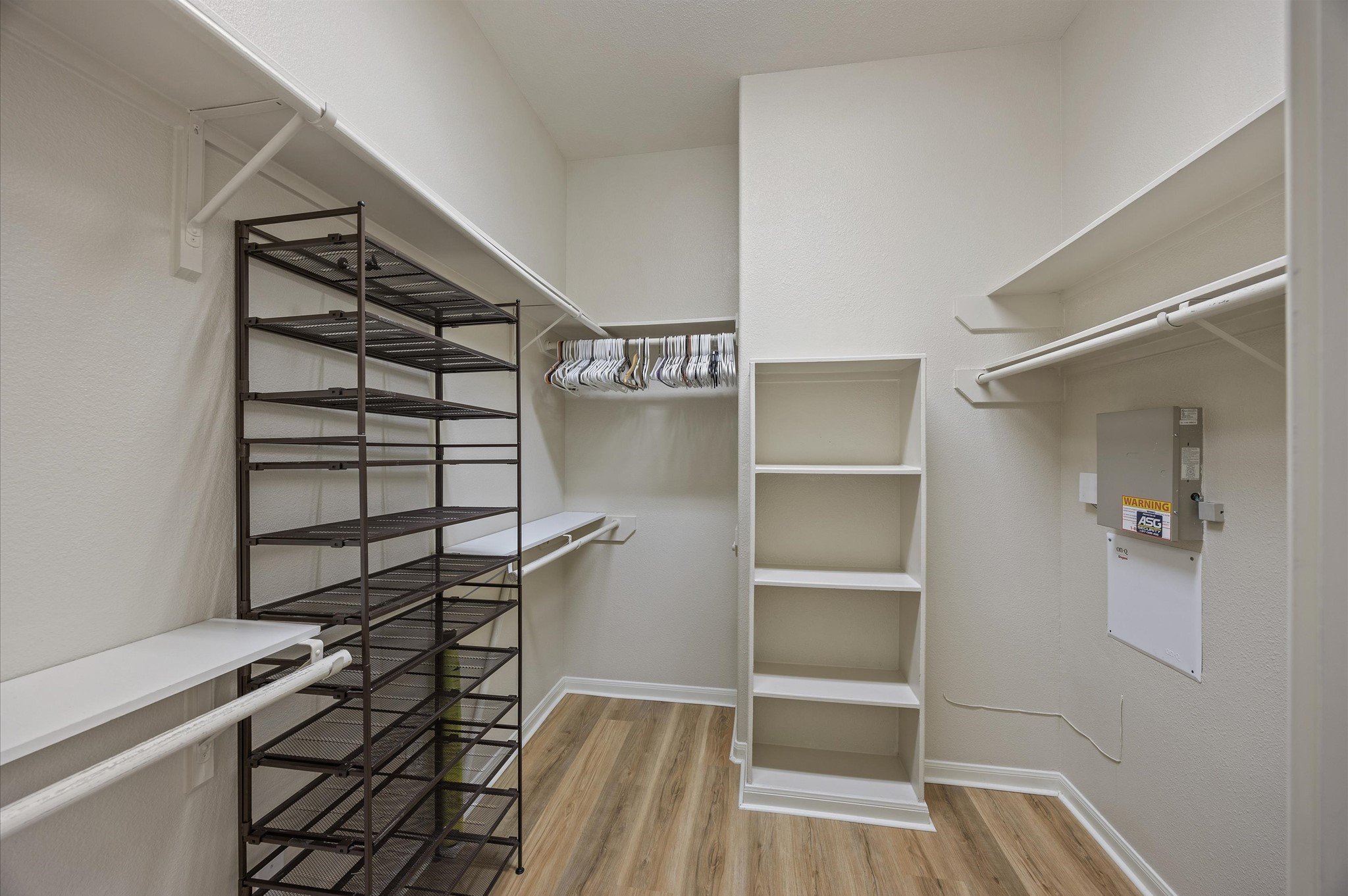 24538 Fort Settlement Drive Spring, TX 77373 - Photo 20 of 29 Spacious walk-in closet with ample shelving and hanging space, featuring built-in shelves and a shoe rack, complemented by wood-look flooring and neutral walls for a clean, modern feel.