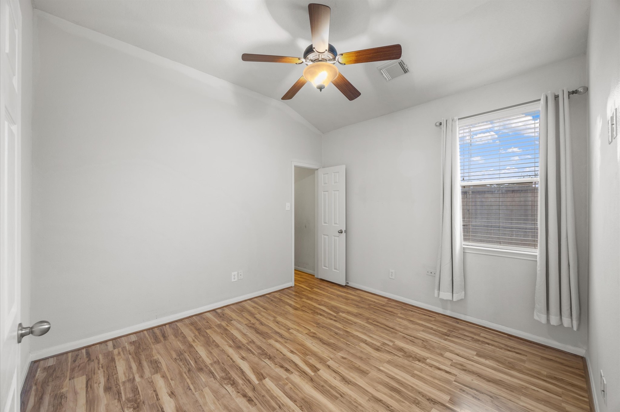 24538 Fort Settlement Drive Spring, TX 77373 - Photo 21 of 29 This room features light-colored walls and wood laminate flooring. It is brightened by a window with white curtains, and a ceiling fan with a light fixture adds comfort.