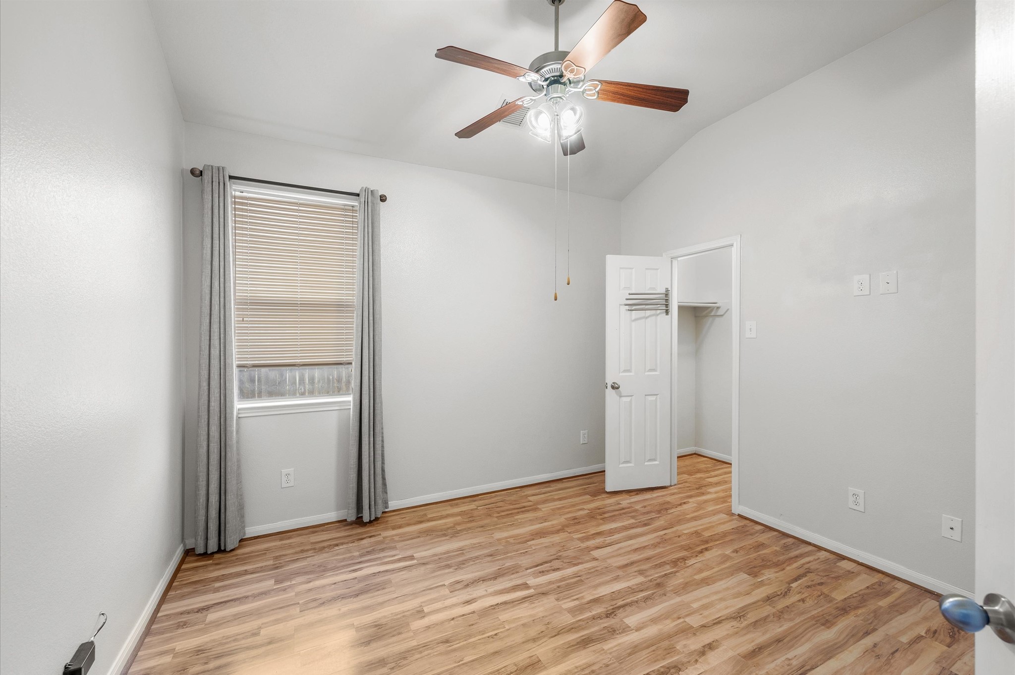 24538 Fort Settlement Drive Spring, TX 77373 - Photo 22 of 29 This room features laminate wood flooring, neutral walls, a ceiling fan, and a window with blinds and curtains. It includes a small closet and has a simple, clean design.