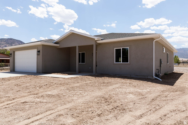 51 West 500 South Monroe, UT 84754 - Photo 2 of 41 Stucco exterior with an attached garage, covered entryway, double-pane windows, and a dark shingle roof