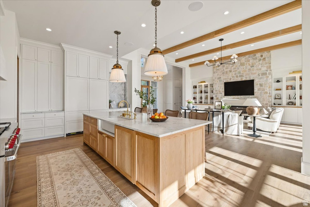 478 South Maple Lakes Drive Mapleton, UT 84664 - Photo 11 of 51 Gourmet kitchen island with a light wood base and stone countertop, featuring an integrated sink and pendant lighting