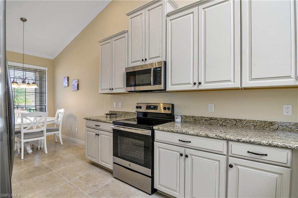 9440 Benvenuto Court, Unit 3204 Naples, FL 34119 - Photo 23 of 28 a kitchen with granite countertop white cabinets and stainless steel appliances