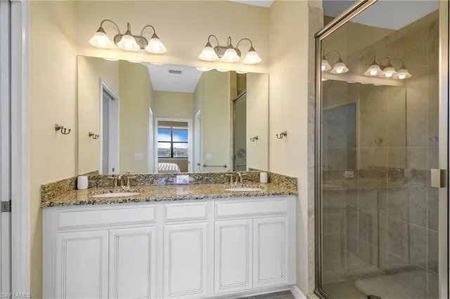 a bathroom with a granite countertop sink a mirror and a shower