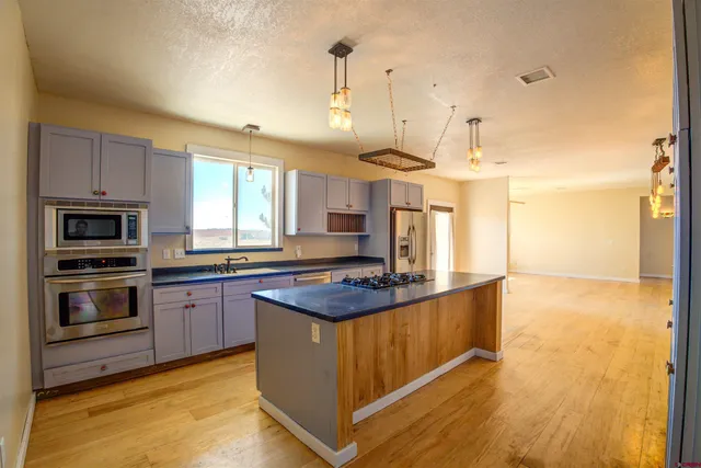 a kitchen with stainless steel appliances granite countertop a sink a stove and a wooden floors