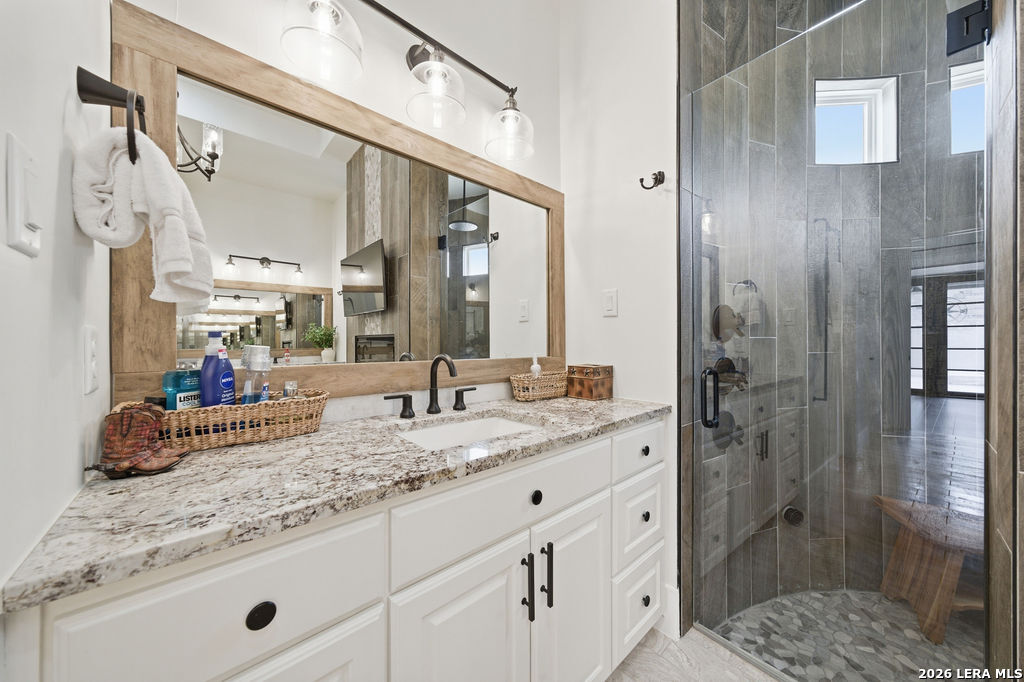 5920 Verden Ridge New Braunfels, TX 78132 - Photo 34 of 61 a bathroom with a granite countertop sink a mirror and shower