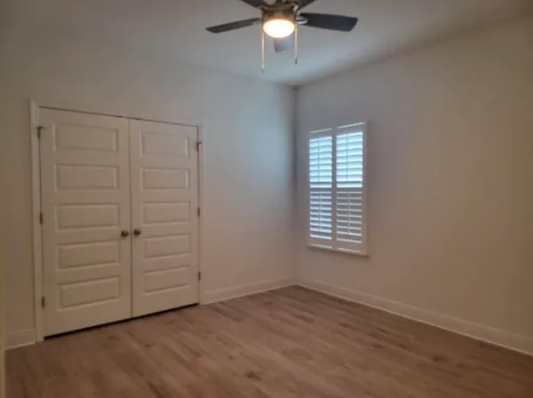 an empty room with wooden floor closet and windows