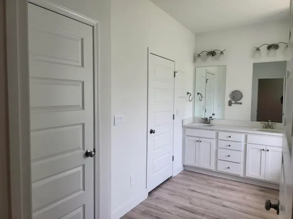 a spacious bathroom with a double vanity sink a mirror and a bathtub