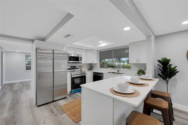 a kitchen with a refrigerator a stove a sink dishwasher a dining table and chairs