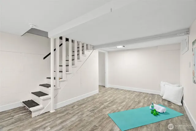 a view of an empty room with stairs and wooden floor