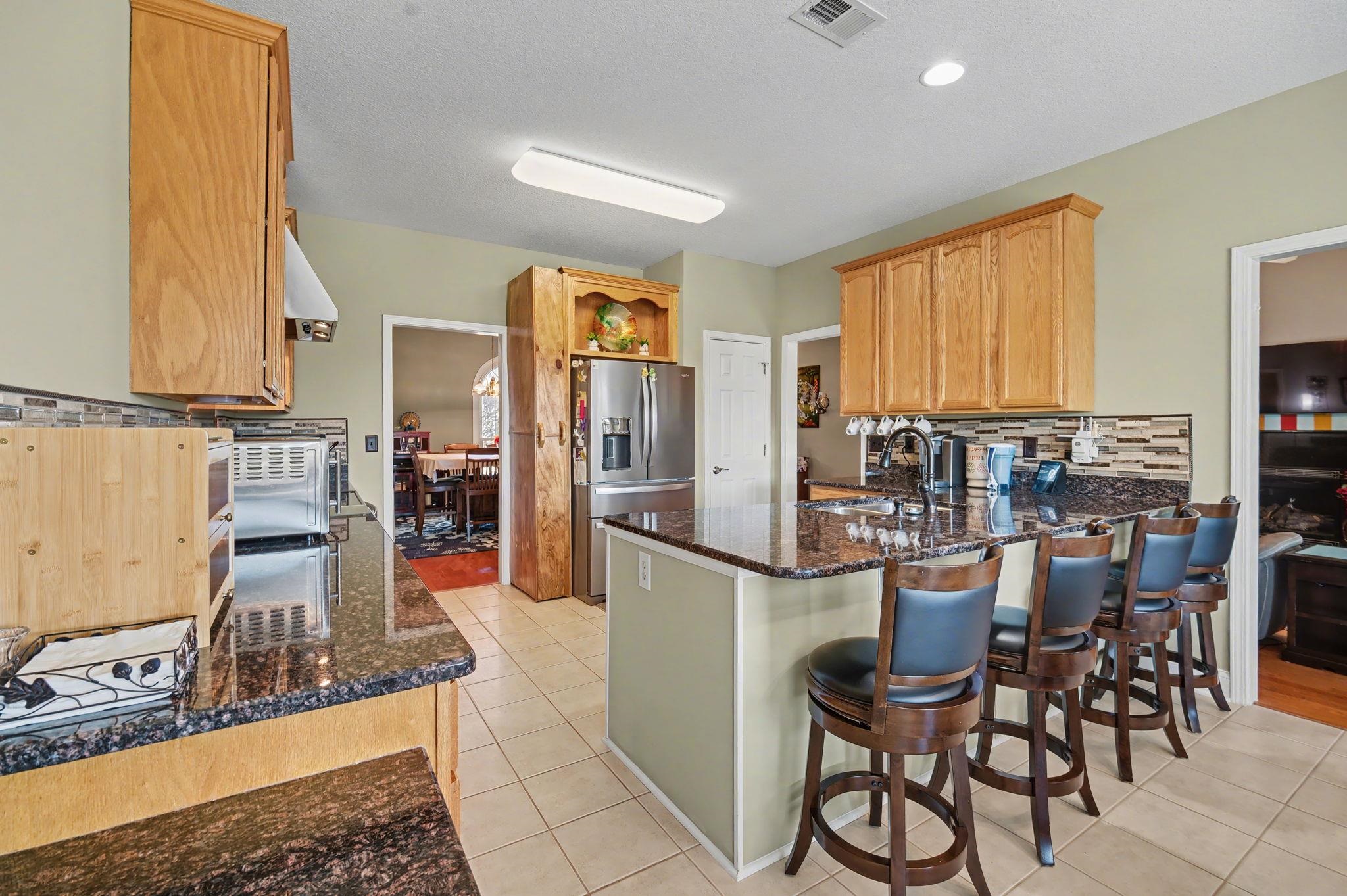 629 Cottontail Trail Myrtle Beach, SC 29588 - Photo 11 of 40 Kitchen with dark stone counters, stainless steel fridge with ice dispenser, a peninsula, a breakfast bar area, and light tile patterned floors