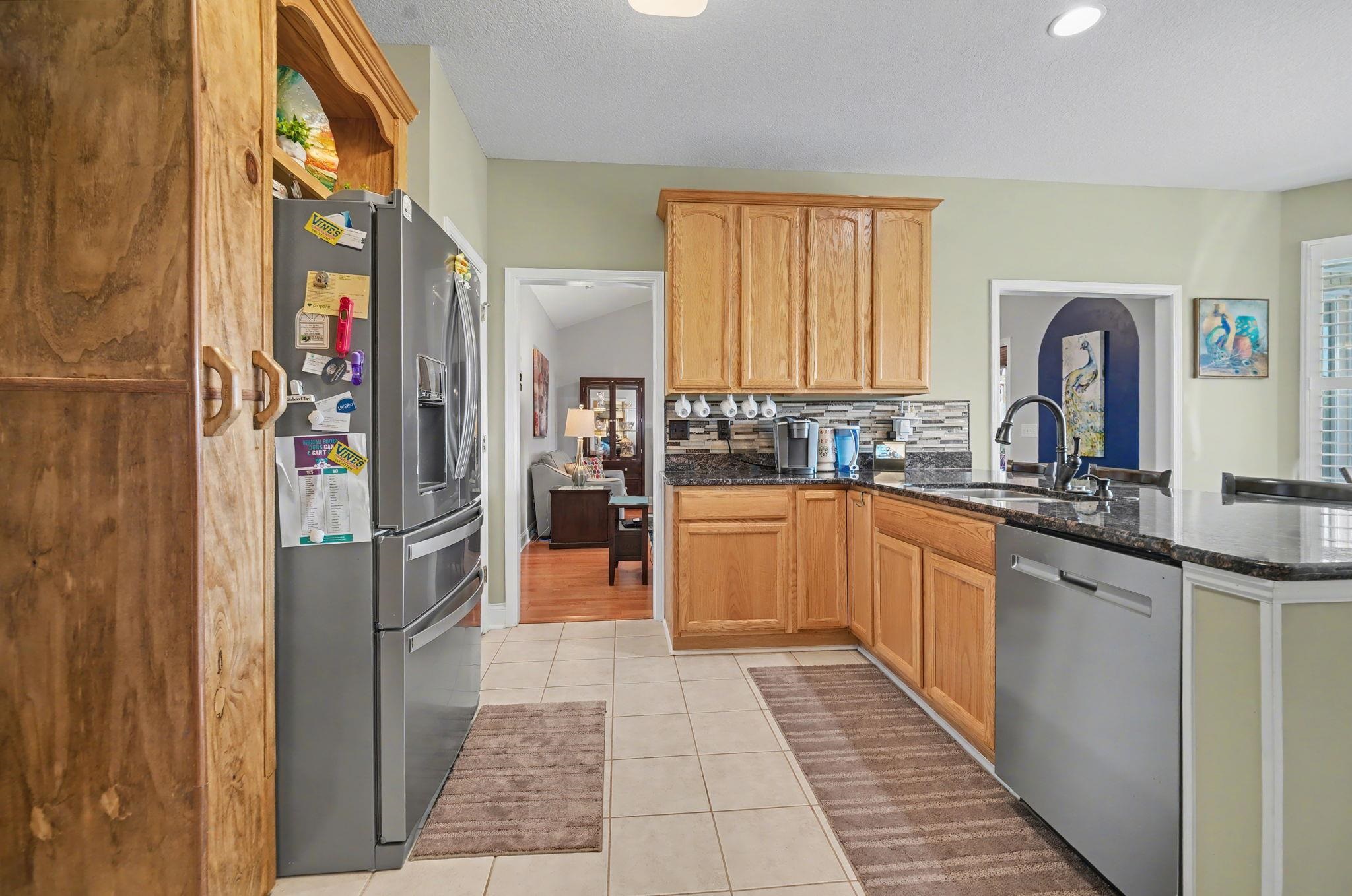 629 Cottontail Trail Myrtle Beach, SC 29588 - Photo 9 of 40 Kitchen featuring dark stone countertops, appliances with stainless steel finishes, light tile patterned flooring, a peninsula, and tasteful backsplash