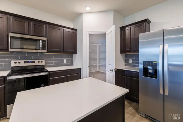 a kitchen with a refrigerator and a stove top oven