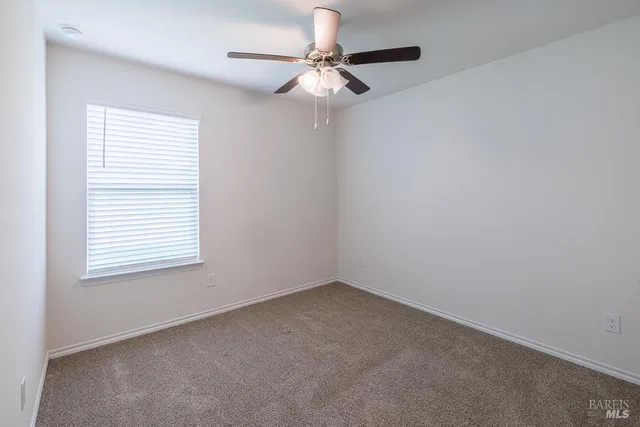 an empty room with a window and a fan