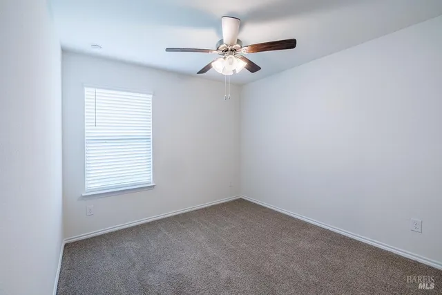an empty room with a window and a fan