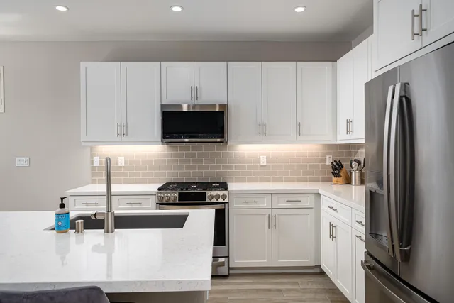 a kitchen with white cabinets and appliances