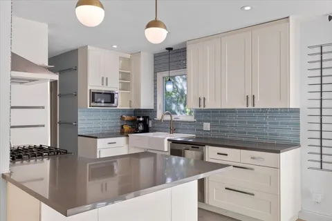 a kitchen with kitchen island granite countertop a sink cabinets and stainless steel appliances