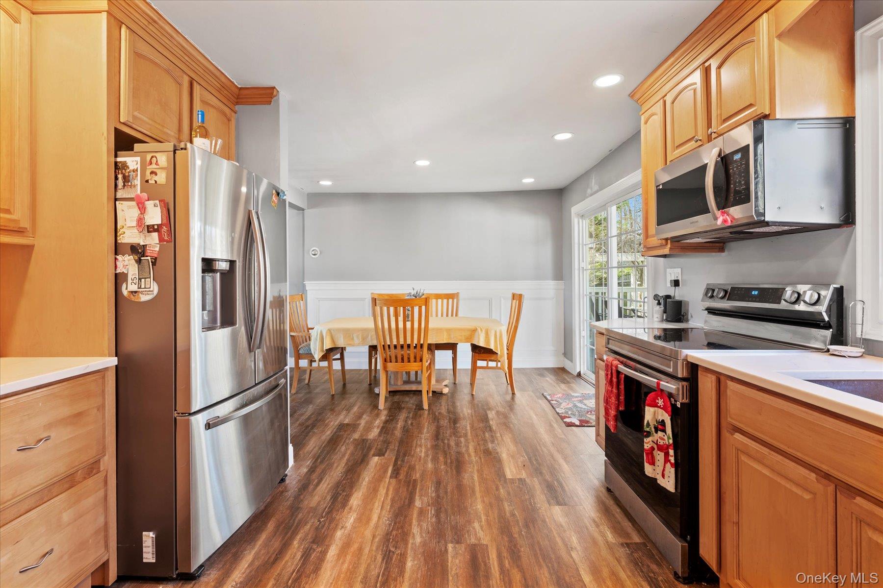 280 Moriches Road St. James, NY 11780 - Photo 10 of 39 a kitchen with stainless steel appliances granite countertop a refrigerator a stove a sink and a dining table with wooden floor