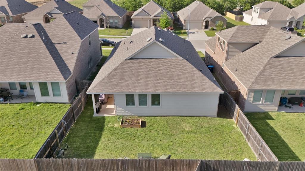 621 Ridgeback Trail Fort Worth, TX 76052 - Photo 19 of 22 Rear exterior featuring a covered patio, multiple windows, and a fenced backyard with a raised garden bed