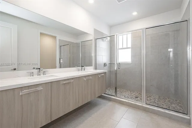 a bathroom with a double sink shower and a mirror
