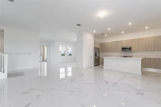a large white kitchen with a refrigerator and white cabinets