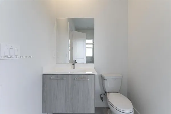 a bathroom with a granite countertop toilet a sink and mirror