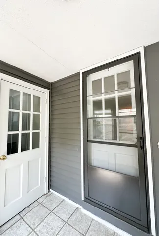 a view of an empty room with wooden floor and windows