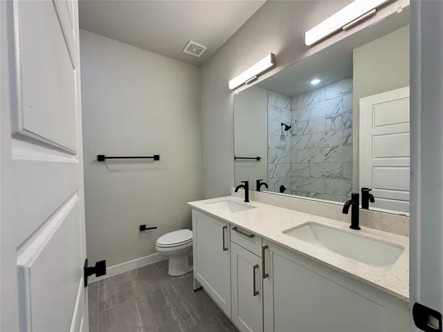 a bathroom with a sink a toilet and a large mirror