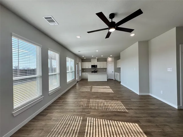 a view of empty room with wooden floor and fan