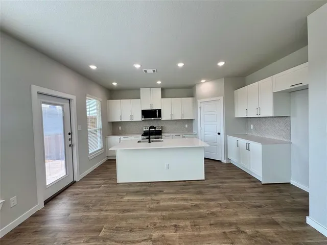 a view of kitchen with kitchen island sink refrigerator and white cabinets