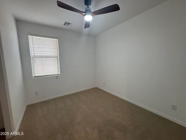 an empty room with a window and a fan