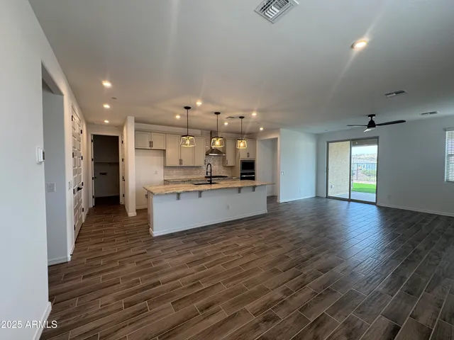 a large kitchen with stainless steel appliances kitchen island a large counter top and a wooden floors