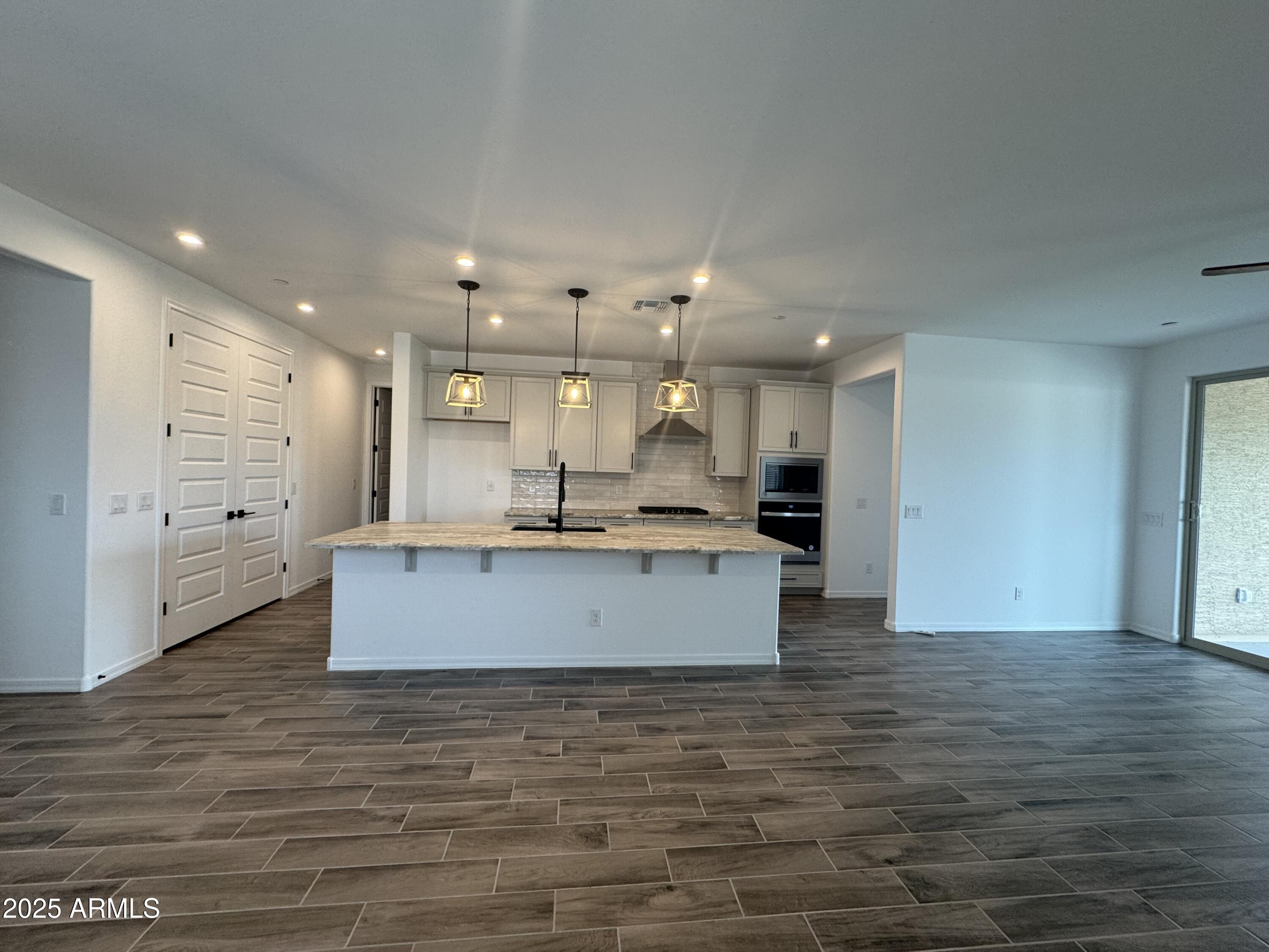 13420 West Eagle Feather Road Peoria, AZ 85383 - Photo 5 of 23 a large room with kitchen island a sink wooden floor and a refrigerator