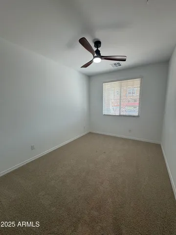 an empty room with a ceiling fan and windows