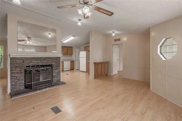 an empty room with wooden floor fireplace and windows